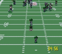 A football field viewed from above displays green grass with white yard line markings and numbers. Multiple player sprites in dark uniforms are positioned across the field at various distances, with one player sprite centered in the lower portion. A yellow timer reading 00:56 appears in the bottom right corner. The perspective shows a zoomed-in view of the playing area with the field extending toward the top of the screen where additional players and game elements are visible.