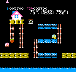 A multi-level platformer stage displays a yellow-and-blue brick architecture with three horizontal platforms connected by vertical columns. A pink character sprite stands on the left side of the bottom platform, while a yellow cheese sprite sits atop the right platform. A small enemy sprite appears in mid-air near the left column. The scene sits above a blue water background. Score counter reads 1-005700 at top left with additional numerical displays, rendered in 8-bit NES-era pixel graphics with a limited color palette of red, yellow, blue, black, and white.