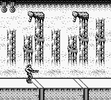 A vertically scrolling level displays multiple cylindrical structures with cross-hatching patterns arranged across the screen against a light background. Three horizontal status bars appear at the bottom of the screen, showing game interface elements. The graphics use low-resolution monochrome pixel art typical of Game Boy hardware, with black sprites and outlines on a white field.
