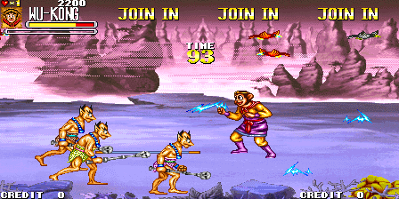 A two-player arcade brawler scene shows four golden-colored characters in combat on a rocky beach platform with purple-tinted water and mountainous terrain behind. Two players control characters on the left and right sides of the screen while enemy fighters engage them. UI elements at the top display player health bars, credit counts, and "JOIN IN" prompts across multiple columns. The sprite artwork uses 16-bit resolution with warm yellow tones for the playable characters set against cool blue and purple background colors.