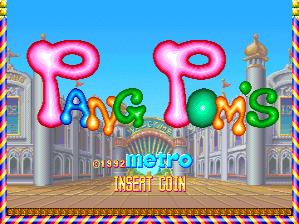 The title screen features a large pink 3D-style logo reading "Pang Pom's" centered above a cityscape with ornate buildings and green domed structures. A blue sky occupies the upper half of the screen with decorative colored borders framing the edges. Below the title, the text "INSERT COIN" appears in yellow lettering on a brown-tan ground section. The overall art style uses bright colors with 8-bit sprite-based graphics typical of early 1990s arcade games.