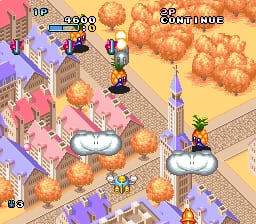 An isometric view of a pastel-colored town layout with two yellow aircraft positioned on circular platforms in the center and right side. Orange flowers or projectiles fill the upper portion of the screen. The left side displays a score panel with "UP" and numerical values, while the right shows "25 REMAINING" text. Purple buildings and pink structures line the streets below. Sprite-based graphics with a soft color palette typical of early 1990s SNES visuals dominate the scene.