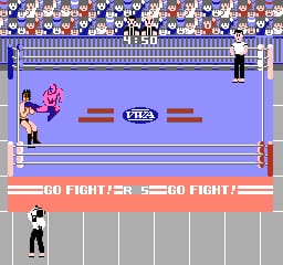 A wrestling ring dominates the center of the screen with a blue mat and red ropes. A pink-skinned wrestler in magenta tights stands on the left side of the ring, while a white-clad referee in black stands on the right. The audience fills the top portion in blue and red rows. Text reading "GO FIGHTER" appears twice on a gray banner below the ring, with a VITA logo centered between them. The lower section shows numbered columns in gray, likely representing a fighter selection or stats interface. The palette uses bright blues, reds, magentas, and whites typical of NES-era graphics.