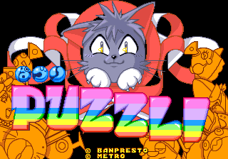 A gray cat character with white facial features and pink nose occupies the center of the screen, surrounded by orange cat illustrations on both sides. Below the cat, the word "PUZZLI" appears in large pink and purple gradient lettering against a black background. A "BANPRESTO" copyright mark is visible in the lower right. The overall composition uses bright colors typical of mid-1990s arcade game title screens, with pixel art styling throughout.