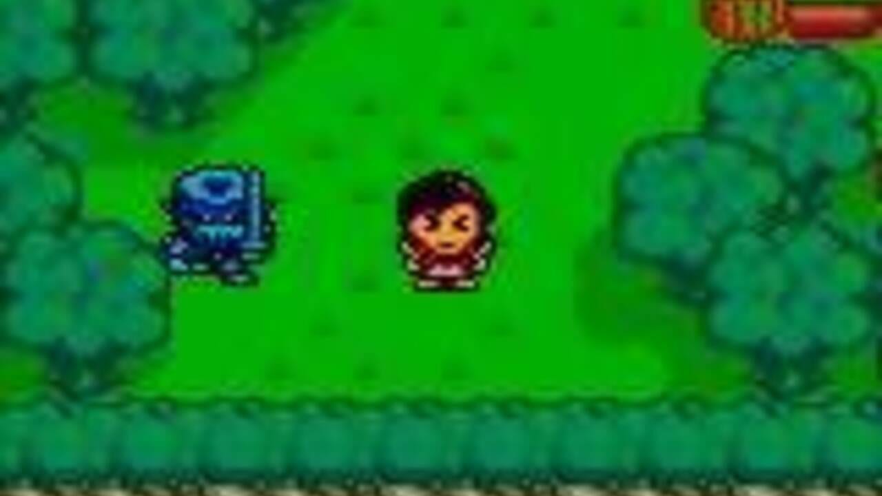 A Game Boy screenshot shows two characters standing in a grassy outdoor area with green foliage and bushes. A blue enemy sprite with a circular design appears on the left side, while a character with dark hair and reddish-brown clothing stands in the center-right. The background is filled with teal-colored vegetation, and a red UI element is visible in the top-right corner. The sprite resolution and color palette are consistent with Game Boy graphics.