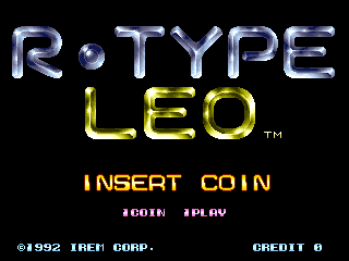 The R-Type Leo arcade title screen features the game logo in metallic blue and yellow lettering centered on a black background. Below the logo, orange text reads "INSERT COIN" with smaller white text showing "#COIN" and "#PLAY" options. The bottom left displays copyright information "© 1992 IREM CORP." in white text, while "CREDIT 0" appears in the bottom right. The entire screen uses a simple color scheme of black background with neon-style blue, yellow, and white text elements typical of early 1990s arcade cabinet displays.