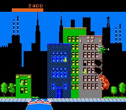 A large monster with red coloring destroys a multi-story building in the center of the screen while surrounded by a blue-tinted cityscape. The building features multiple brown and gray window sections arranged in rows. To the left stands a smaller blue building with vertical striping, and green trees dot the ground level. The HUD displays "3 AGO" in the upper left corner against a black bar. A green grass line marks the ground, with silhouetted skyscrapers visible in the background cityscape. The pixel art uses a limited color palette typical of NES-era games.