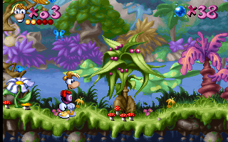 Rayman stands on a green platform in the center-left of a colorful jungle level with purple and pink flowers, vines, and mushrooms forming the background. The HUD displays Rayman's health as 3 red hearts in the top-left corner and a score counter showing 338 in the top-right. A brown enemy creature appears on the platform to the right of Rayman. The level features layered parallax scrolling with green grass in the foreground, a blue sky, and vibrant magenta vegetation throughout. The art style uses 16-bit sprite animation with bright primary and secondary colors typical of early-to-mid 1990s platformer graphics.
