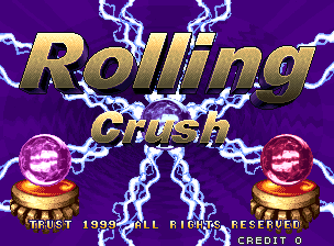 The title screen displays 'Rolling Crush' in large gold italicized text across the center, set against a purple background with white lightning bolts radiating outward. Two identical golden spheres with red and yellow concentric rings sit symmetrically on either side below the title, also surrounded by lightning effects. At the bottom of the screen, white text reads 'TRUST 1999 ALL RIGHTS RESERVED' and 'CREDIT ON', with pixelated arcade-style lettering typical of late 1990s arcade cabinets.