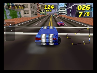 A blue race car with white racing stripes drives down an urban street lined with buildings. The car is centered in the view with a yellow road divider ahead. Competitor vehicles appear on either side. The HUD displays lap time 0:16.06 in the top-left, race position indicators showing 124 and 25 points in the top-center and top-right, and lap counter 026/7/8 in the top-right corner. The 3D graphics use solid polygonal modeling typical of N64-era arcade racing games. The perspective is from directly behind the player vehicle.