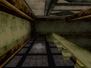 A first-person perspective view of a deteriorated indoor corridor with wooden ceiling beams and metal railings lining both sides. The floor features a checkered tile pattern in gray and dark tones. Walls show peeling paint and rust stains, with a yellowish-green discoloration on the left wall. The passage extends forward into shadow, creating depth through linear perspective. The lighting casts shadows from the railings across the floor, emphasizing the cramped, run-down atmosphere of the space.