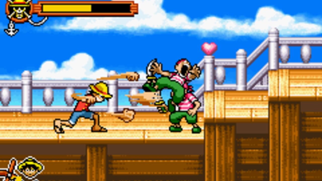 A pirate character in yellow hat and red shirt attacks a large green enemy with pink accents on a wooden ship deck. A red heart icon floats above the combatants. The HUD displays a yellow health bar at top-left with a pirate emblem. White railings and wooden structures frame the scene against a bright blue sky with white clouds. Pixelated sprite-based graphics typical of Game Boy Advance handheld gaming.