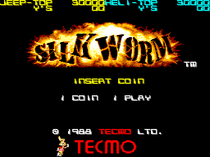 The Silk Worm title screen displays the game's logo in large fiery orange and yellow letters at center, with a glowing flame effect around the text. Below the logo, white text reads "INSERT COIN" followed by menu options "1 COIN" and "1 PLAY" in a simple pixelated font. The background is solid black. At the bottom, copyright information shows "© 1998 TECMO LTD." in red text, followed by the Tecmo company logo in red letters. The overall color scheme uses bright orange, yellow, white, and red against the dark background.