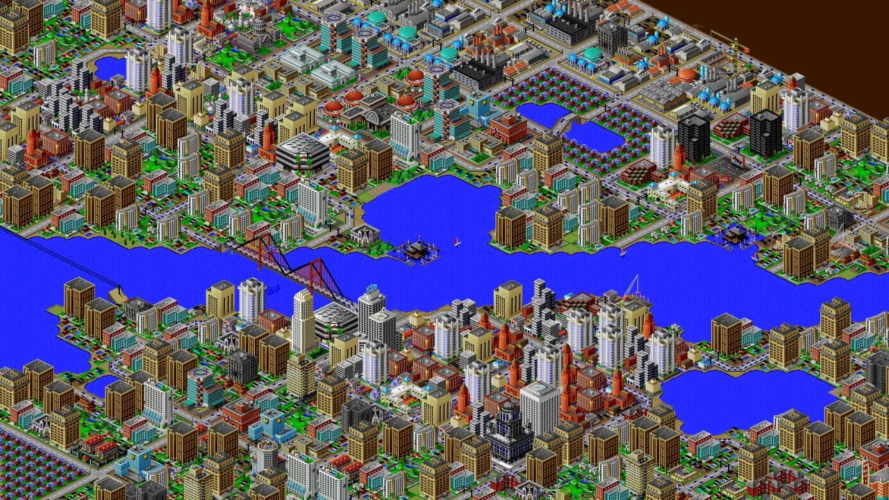 An isometric city layout with multiple zones of dense urban development separated by bright blue waterways and bridges. Buildings vary in color—tan, red, white, and cyan—arranged in grid patterns across the terrain. Green parks and tree clusters dot the landscape. The upper portions show organized residential and commercial sectors, while the center features a prominent red suspension bridge crossing blue water. The lower area contains denser development with taller structures. A small sailboat appears on the water. The pixel art uses a limited color palette typical of early 1990s PC graphics, with buildings rendered in isometric perspective and sharp edges throughout.
