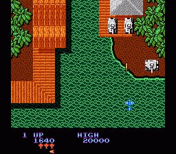 A top-down scrolling view of a military compound with brown tile roofing, green grass terrain, and orange brick buildings arranged around the perimeter. A small blue helicopter sprite is visible in the center-lower portion of the screen. The top-left corner displays the score as 540 with a high score of 90000 in white text. Green trees line the edges of the map. The color palette consists of brown, green, orange, and gray pixels typical of NES-era graphics.