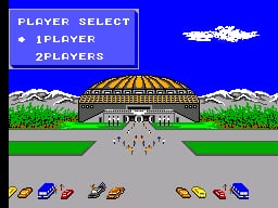 A Player Select menu appears in the upper left with options for 1Player and 2Players highlighted in blue. Below, a stadium with a brown roof and snowy mountains in the background sits centered on a grass field with a gray road leading to it. A white cloud floats in the bright blue sky above. At the bottom, a row of seven colored vehicles—yellow, blue, red, purple, green, orange, and another colored car—are lined up on the gray road, rendered in low-resolution 8-bit sprites typical of SMS-era graphics.