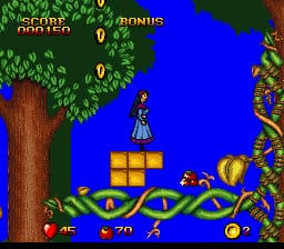 Snow White stands on a blue platform in the center of the screen, surrounded by yellow brick blocks arranged in a curved pattern. A large tree with green foliage occupies the left side, while ornate brown architectural elements frame the right edge. The blue background suggests a sky or outdoor setting. A red apple and yellow coins are visible on the platform. The upper left displays score and status information in yellow text against the dark background. The art style features colorful 16-bit sprites and a parallax background typical of early 1990s SNES platformers.