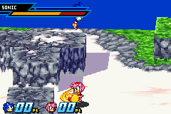 A GBA-resolution screenshot shows two characters in combat stance on a rocky gray platform against a blue sky. Sonic stands on the left side while an opponent faces him on the right. Below them are two health bars displaying red and blue colors, with numerical values visible. The environment features brown stone blocks arranged in a platform layout, with green grass visible at the far right edge. The art style uses flat-shaded 3D models rendered in GBA-era graphics.
