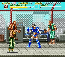A fighting game scene displays three characters on a tiled stage floor with a checkered background and stone wall structure. In the center, a blue-clad fighter in a crouching stance faces two opponents in green and brown outfits positioned on either side. The top of the screen shows a cyan health bar for the player character on the left, numerical score displays, and a beige-colored opponent health indicator on the right. The sprite artwork uses low-resolution pixel graphics typical of early 1990s SNES games, with distinct character outlines and limited color palettes.