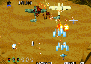 A top-down aerial shooter displays a tan-colored desert landscape with a multi-colored aircraft at screen center firing projectiles downward. Enemy formations of blue geometric shapes advance upward in organized columns, with orange explosion effects visible below them. The HUD shows 'IP' indicator, score '101100', 'LEVEL 3', and 'CREDIT 00' at the bottom. Scattered white pixels represent additional projectiles or environmental elements across the sandy terrain. The sprite-based graphics use a limited color palette typical of mid-1990s arcade hardware.