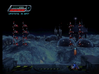 A 3D nighttime lunar landscape features multiple geometric alien invader structures scattered across a blue-tinted terrain with craters and rocky formations. Several tall rectangular enemy units stand in the middle distance while others are positioned to the left and right sides. A player-controlled craft with a blue glow appears in the lower right corner. A game UI bar with health or ammo indicator is visible at the top left of the screen. The scene uses a dark palette with cyan and orange accent lighting on the enemy structures.