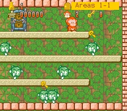 A character sprite resembling a monkey stands in the upper-left area of a green grassy level with brown brick borders. The screen displays a score of 000000 and a value of 0 in the top-left corner. Three white cloud-like platforms are stacked vertically in the center, with small white ghost enemies positioned on the middle and lower platforms. The level uses a repeating green grass tile pattern background with brown brick walls framing the play area. The overall visual style features low-resolution SNES-era sprites and a simple platformer layout.