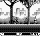 A side-scrolling platformer scene in monochrome Game Boy graphics shows Spider-Man as a small dark sprite in the center-right of the screen, facing left. Two bare trees with detailed black branches frame the urban background, with white building outlines visible behind them. The ground is a solid black platform. A score display reads "0000000" on the lower left, with additional UI elements showing "11" and "451" on the lower right. The low resolution and limited color palette are characteristic of early 1990s Game Boy handheld graphics.