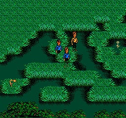 A top-down view of a grassy terrain with dark water channels cutting through patches of light green grass. Three small character sprites in red, yellow, and blue stand grouped together in the center-left area. The landscape features irregular water formations bordered by lighter grass tufts, creating a natural maze-like environment. The NES-era pixel art uses a limited palette of greens, dark blue, and bright primary colors for the characters. Small trees or vegetation markers appear scattered across the grassy areas.