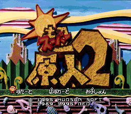 The title screen displays a large golden character with a star-shaped head on the left side, rendered in a tan and red color scheme against a bright blue sky background with yellow and purple horizontal stripes. Japanese text appears in the center and lower portion of the screen in white characters against the colored background. The art style uses bold outlines and flat colors typical of SNES-era sprite graphics. Green grass or foliage is visible at the bottom edge of the screen.