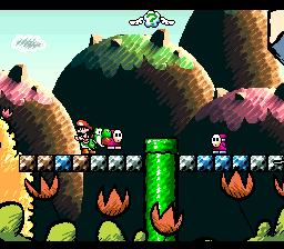 A side-scrolling platform level features Yoshi in the lower-left area, with Baby Mario visible in the HUD at top-left. The terrain displays colorful plant-like structures in green and pink tones with brown cylindrical segments, surrounded by flaming obstacles and grassy platforms. The visual style uses Mode 7-style parallax layering with soft-focus backgrounds, creating depth across the scene. The sprite palette and pixel resolution are characteristic of 16-bit SNES graphics.