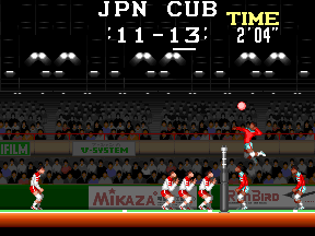 A volleyball match in progress on a pixelated indoor court. The scoreboard at top displays 'JPN CUB' with time '11-13' and score '2 04'. Red-uniformed players occupy the right side of the court in defensive positions, while white-uniformed opponents are visible on the left. A red volleyball floats above the net in mid-play. Spectators fill the stadium background in rows of red and blue pixels. Sponsor text including 'Mikaza' and 'BIRD' appears on advertising boards along the court perimeter. The sprite-based art uses a limited color palette typical of late-1980s arcade graphics.