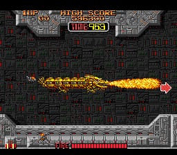 A bright golden flame projectile streaks across the center of a dark tile-patterned playing field in this SNES shoot-em-up. The score display reads 533 at the top center, with the current stage and high score visible in the header. A red heart power-up floats on the right side of the screen. The bottom of the screen shows a red health or weapon bar interface. The overall art style features low-resolution sprites and pixelated graphics typical of early 1990s console arcade games.