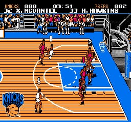 A basketball court viewed from above shows two teams in red and white uniforms positioned on the wooden floor. The blue paint defines the key area in the center. The scoreboard at the top displays team names and scores, with the home team showing 90 points and the away team 91. Player sprites are rendered in low resolution with minimal detail, typical of NES-era graphics. The court features clear lane markings and the three-point line in white, with the baseline and sidelines visible. Team benches with seated players appear along the edges of the court in the background.