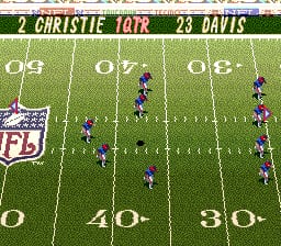 A football field overhead view displays two teams lined up in formation across the gridiron. Blue players occupy the left side while purple players position on the right, separated by yard line markings at 0, 40, and 80. The scoreboard header shows "CHRISTIE 10" and "DAVIS 23" in yellow text, with a small NFL shield logo visible in the upper left corner. The 16-bit sprite graphics show a top-down perspective typical of SNES football gameplay, with pixel-art player figures rendered in small scale against the green field background.