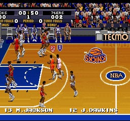 A basketball game in progress on a wooden court with players from two teams positioned around the key. The team in orange jerseys has possession of the ball near the baseline on the left side, while the opposing team in blue defends. A scoreboard displays the game clock and score at the top. Player names appear at the bottom of the screen identifying M. Dickson and J. Driskins. The court features the NBA logo and a team logo in the center. Spectators fill the stands in the background. Sprites are rendered in 16-bit resolution with limited animation frames typical of early 1990s basketball games.
