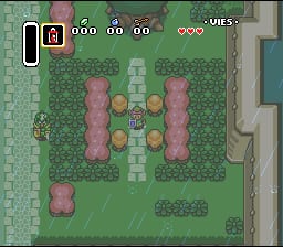 A top-down view of a green grass courtyard with a central tiled area containing four yellow circles arranged in a square pattern. A small green-clad character sprite stands in the middle. Pink rectangular structures flank both sides of the courtyard. The HUD displays a minimap in the upper left, numbered counters showing 000 at the top center, and three red heart icons in the upper right corner. Gray stone walls and building structures border the scene. The pixel art uses a limited color palette typical of early 16-bit games.