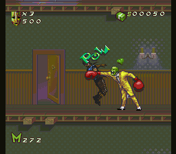 The player character, rendered in green with yellow accents, performs a high kick toward an enemy in a brown suit positioned to the right on a brick-patterned indoor floor. A green "KICK" label hovers above the character. The top-left displays health and power icons alongside a 500 score counter; the top-right shows five circular power-up icons. A purple door is visible on the left side of the room, and a gray stone structure appears in the upper right. The bottom-left corner shows 222 remaining time units. The scene uses a 16-bit pixel art style with a muted green-brown color palette.
