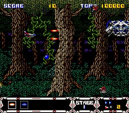 A vertical-scrolling shooter level with a forest setting dominated by three tall, textured brown tree trunks in the center and right side. A player aircraft hovers in the lower-left portion of the screen. A white enemy sprite appears in the upper-right corner. The HUD displays score and top score at the top left, enemy count and stage number in the center, and a weapon/power-up bar at the bottom. The color palette is predominantly browns and greens with bright accent colors for UI elements, rendered in 16-bit sprite graphics.
