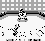 A Game Boy screenshot displays a sports minigame interface featuring Buster Bunny's head at the top center with a game status logo. Below is a white play field with geometric shapes—a diamond outline and rectangular forms—positioned across the screen. Navigation icons and game information appear along the bottom in monochrome green-tinted pixels typical of original Game Boy hardware. The overall layout suggests a turn-based or menu-driven sports activity selection screen.