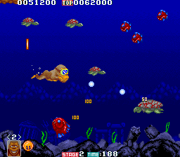 A brown monkey-like character floats in the center of a dark blue scrolling level filled with brown stone platforms and enemies. Red and orange crustacean creatures appear throughout the upper screen, while small purple spheres float mid-stage. A yellow scorpion-type enemy sits on the right side. The HUD displays a score of 0051200 and 0062000 in the top corners, with "STAGE 2" and "TIME: 100" visible at the bottom left, alongside a row of pixelated enemy sprites and icons representing remaining lives or power-ups.