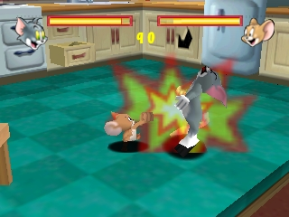 Tom and Jerry face off in a teal-floored kitchen arena with brown wooden furniture and cabinets lining the walls. A bright green and yellow starburst explosion effect erupts between the two characters in the center of the screen. Health bars appear at the top in orange and yellow. The 3D models use solid colors with minimal shading typical of N64 graphics, set against a beige-walled domestic interior.