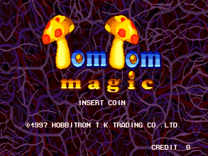 Two yellow cartoon characters with round bodies and limbs face forward against a purple background with pink vine-like patterns. Blue text reading "Tom Tom magic" appears between them in a large pixelated font. Below, white text states "INSERT COIN" with a copyright notice "©1997 HOBBITRON T.K.TRADING CO.,LTD." and "CREDIT 0" displayed in the bottom right corner. The overall aesthetic uses bright primary colors on a dark, textured backdrop typical of late-1990s arcade graphics.