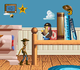 A bedroom interior in 16-bit pixel art shows Woody the cowboy character standing on a wooden floor in the center-left, facing right. Behind him is a bed with pink pillows and a white frame. To the right stands a wooden dresser with blue books stacked on top and a small object. A window with a blue sky and white cloud appears in the upper background. Simple UI icons in the top-left and top-right corners display a computer monitor and question mark symbols. The art style uses a limited color palette with brown wood tones, blue walls, and sprite-based animation typical of SNES-era games.