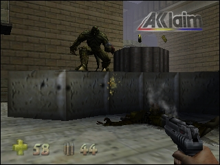 A first-person shooter view shows a muscular creature with horns standing atop dark cylindrical barriers in an industrial concrete corridor. The player's weapon, a rifle with visible ammunition counter, occupies the lower right. The HUD displays health (59), ammo counts, and weapon icons along the bottom. Overhead, a glowing Acclaim logo is mounted on the brick wall. The scene uses early N64 polygon graphics with flat-shaded surfaces and limited texture detail.