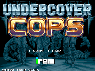 The title screen displays "UNDERCOVER COPS" in large golden outlined letters against a dark blue background. Below the title are two pixelated character sprites in dark clothing, positioned side by side. At the bottom, white text reads "1 COIN 1 PLAY" on the left, with the green Irem logo centered. Copyright text "©1992 IREM CORP." appears in the lower left corner. The overall color palette consists of blues, golds, and greens typical of early 1990s arcade graphics.