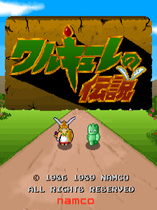 The title screen displays large yellow and red pixelated Japanese text at the top center against a brown stone wall background. Below the title, a green grass field stretches horizontally with two small sprite characters standing on a tan dirt path in the center—one appears to be wearing brown and the other green. A blue sky with white clouds occupies the upper portion. Copyright text reading © 1985 1989 NAMCO and ALL RIGHTS RESERVED appears at the bottom, followed by the Namco logo in red text.