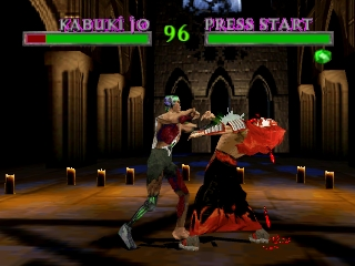 Two fighting game characters clash in a candlelit stone chamber with ornate pillars and arched doorways. The character on the left wears dark clothing and executes a punch toward the red-clad opponent on the right. Health bars for both fighters appear at the top—labeled Kabuki and Press Start at 96 health. The background features warm-toned stone architecture with lit torches along the floor, rendered in 3D polygonal style typical of mid-1990s fighting games.