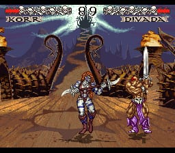 Two characters face each other in a desert arena at sunset. The left fighter wears metallic armor, while the right fighter is dressed in purple robes. Massive ornate ship prows or structures flank both sides of the battlefield. Golden brazier flames burn in the background. Sand dunes and a purple-orange sky with clouds form the distant scenery. Text labels reading "KORK" and "DIVAON" appear at the top of the screen. The sprite-based graphics use a warm color palette of browns, golds, and purples typical of mid-1990s fighting game aesthetics.