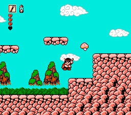 A small red character stands on a brown stone platform in the center-right of the screen, surrounded by green trees and a large brown rock formation to the right. The turquoise sky contains two white clouds and a floating red enemy in the upper-middle area. Pink blocks form a clustered structure on the right side. A HUD in the upper-left corner displays a score meter and life indicator. The 8-bit sprite art uses bright primary colors with distinctive pixelation typical of early NES titles.