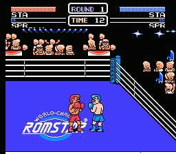 A boxing ring scene displays two pixelated fighters in the center on a bright blue mat with white boundary lines. The top HUD shows health bars for both fighters on either side, with "ROUND 1" and "TIME 12" in the center. Spectator sprites line the upper bleachers in tan and red colors. The "RUMST92" logo appears in blue text on the mat. Opponents' portraits are visible in the upper corners, and additional crowd figures sit in the background bleachers on the right side. The NES-era sprite work uses limited color palettes typical of early-90s fighting game graphics.